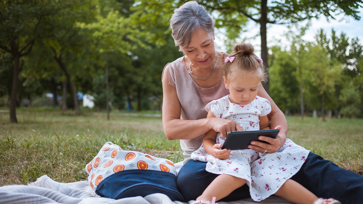 Close up of Grandmother and granddaughter using tablet in nature