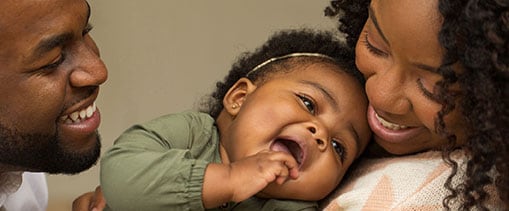 Foto de una pareja y su bebé que están sonrientes.