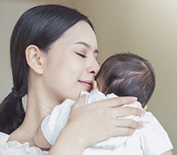 A woman holds her young baby.