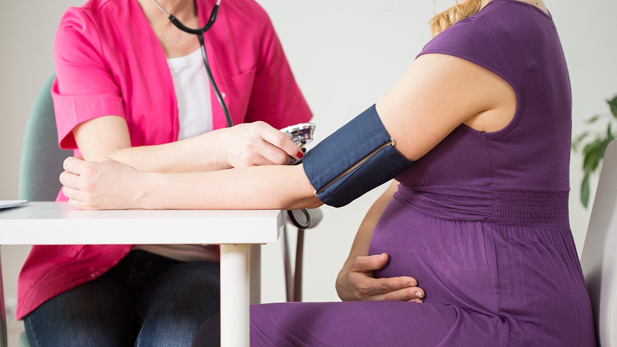 A doctor measuring a pregnant woman's blood pressure.