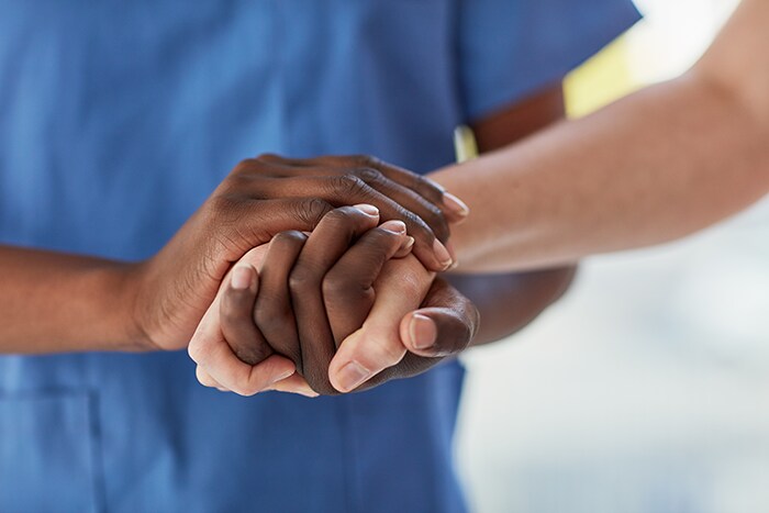 photo of a person in scrubs holding the hand of a patient