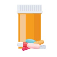 Pastillas delante de un frasco amarillo de medicamentos.