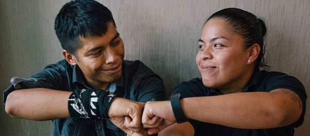 A man and female sitting and smiling with connecting fist pumps. National Latinx AIDS Awareness Day. October 15. Raise awareness about HIV testing and prevention to Latinx communities and provide them with information on access to care.