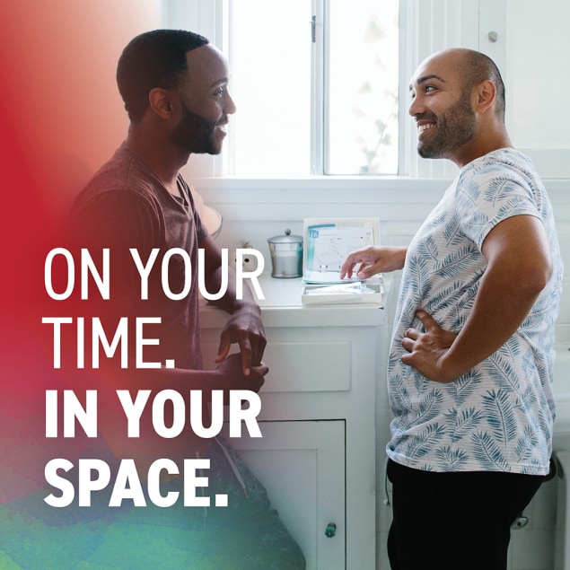 Two men stand facing each other in a bright home bathroom. An HIV self-test rests on the bathroom sink. Text says: On your time. In your space.