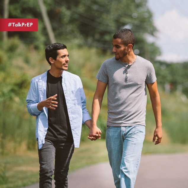 Two men walking outside, holding hands, and smiling. Text says: Talk PrEP.