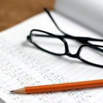photo of a notebook, glasses and a pencil