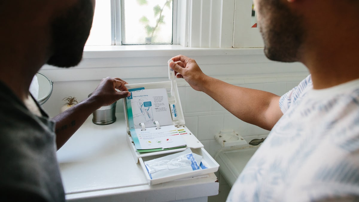 Two people looking at an HIV self-test kit.