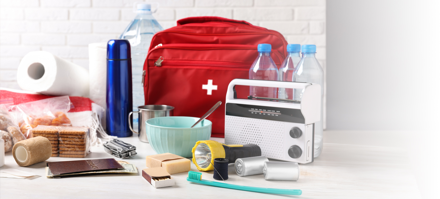 Disaster supply kit on white table near brick wall