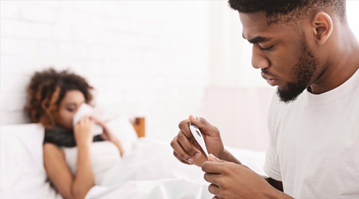 man checking the temperature of wife sick in bed