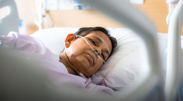 Elderly woman lying in hospital bed.
