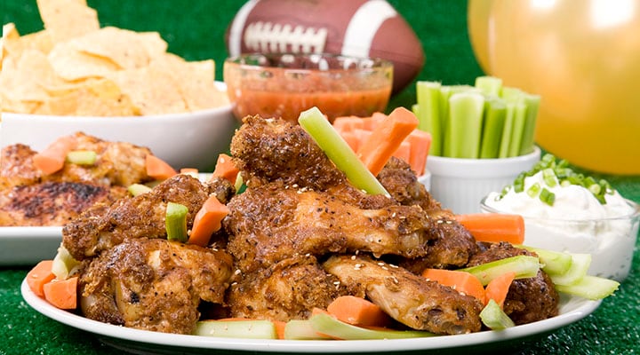 Plate of chicken wings in front of a football