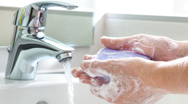 Una persona lavándose las manos y con jabón