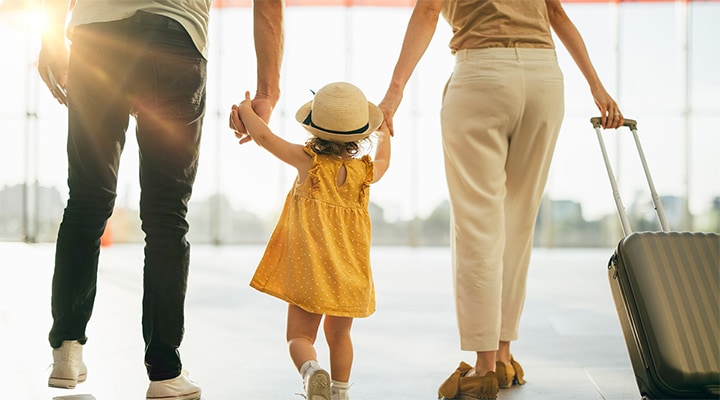 Parents holding daughter’s hand and walking through airport