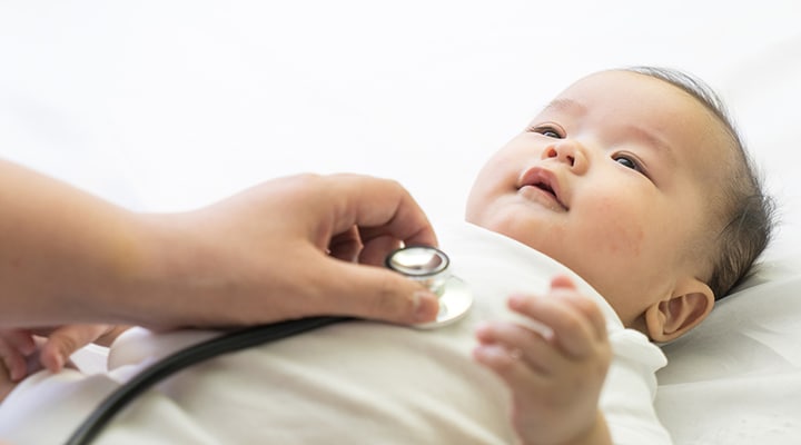Médico examina a un bebé con un estetoscopio