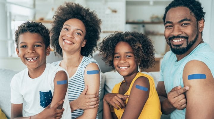 Smiling family with adhesive bandages on their arms.