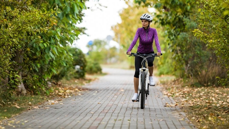 Woman riding bike on brick path.