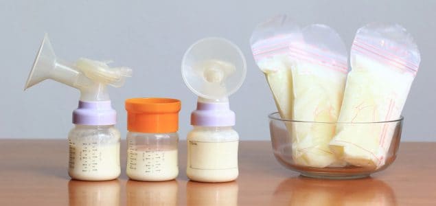 Biberones y bolsas de almacenamiento de leche materna congelada para un nuevo bebé en una mesa de madera