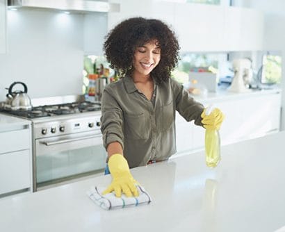 Una mujer joven limpiando un mostrador de cocina en casa