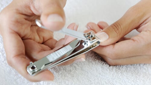 Cutting nails with nail clippers.