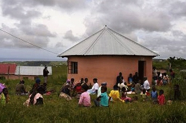 Circular building surrounded by South African people waiting in the grass for medical care