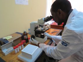 Scientist using a microscope to track diseases of concern.