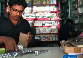 Indian pharmacist measuring medication on a counter in a pharmacy