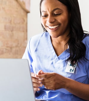 Healthcare worker smiling at computer screen