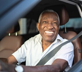 Image of a smiling older man driving a car