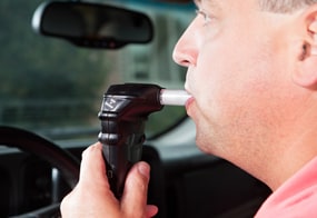 Image of a man using an ignition interlock device before driving