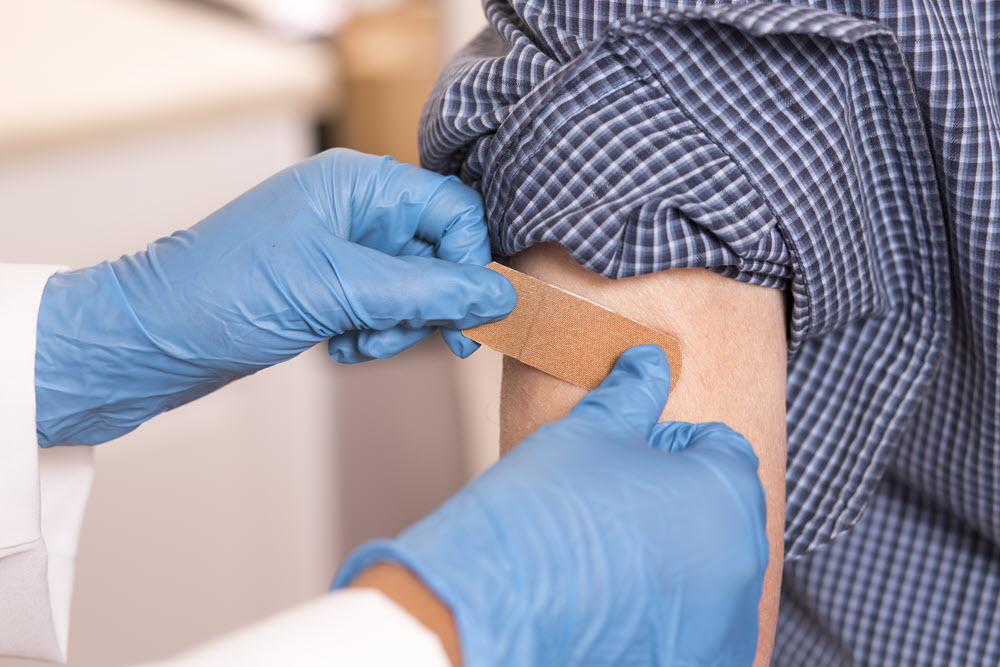 healthcare professional placing bandage on person's arm