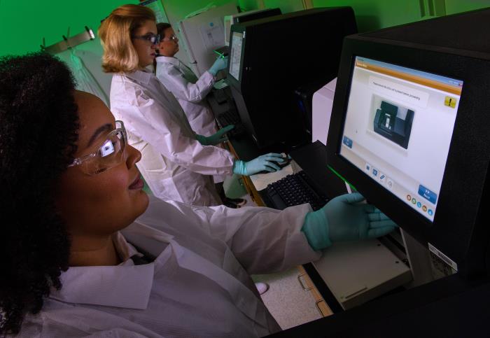 Public health laboratory professionals setting up a bacterial DNA sequencing run on a sequencing instrument.