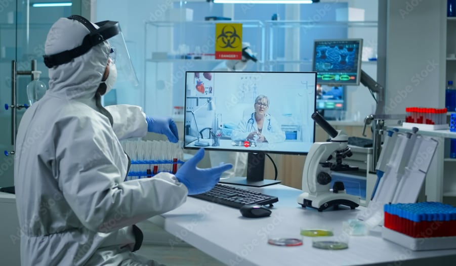Public health lab worker in personal protective equipment on a video call with a healthcare provider
