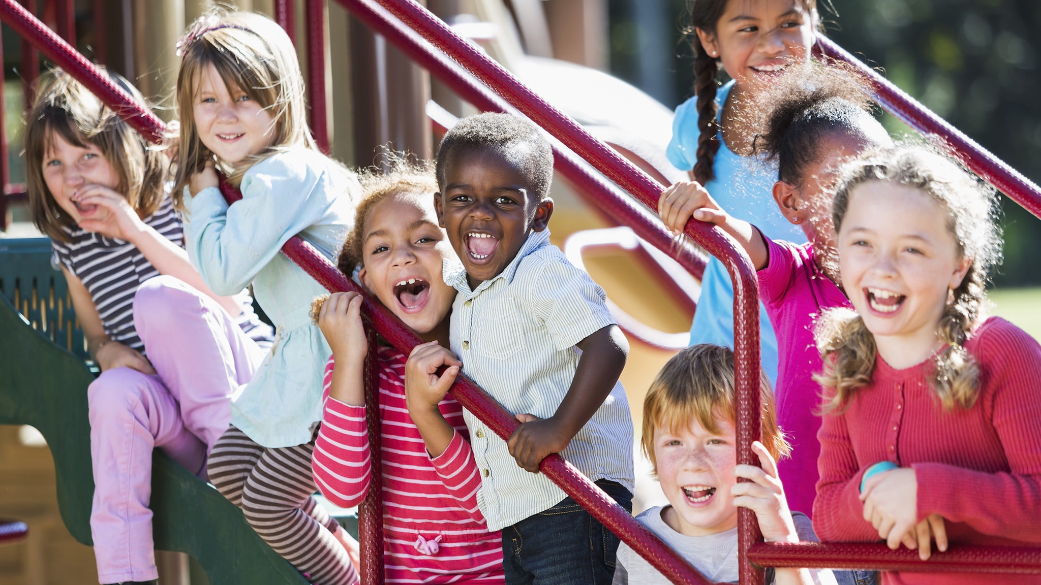 Smiling group of kids on an outside staircase.