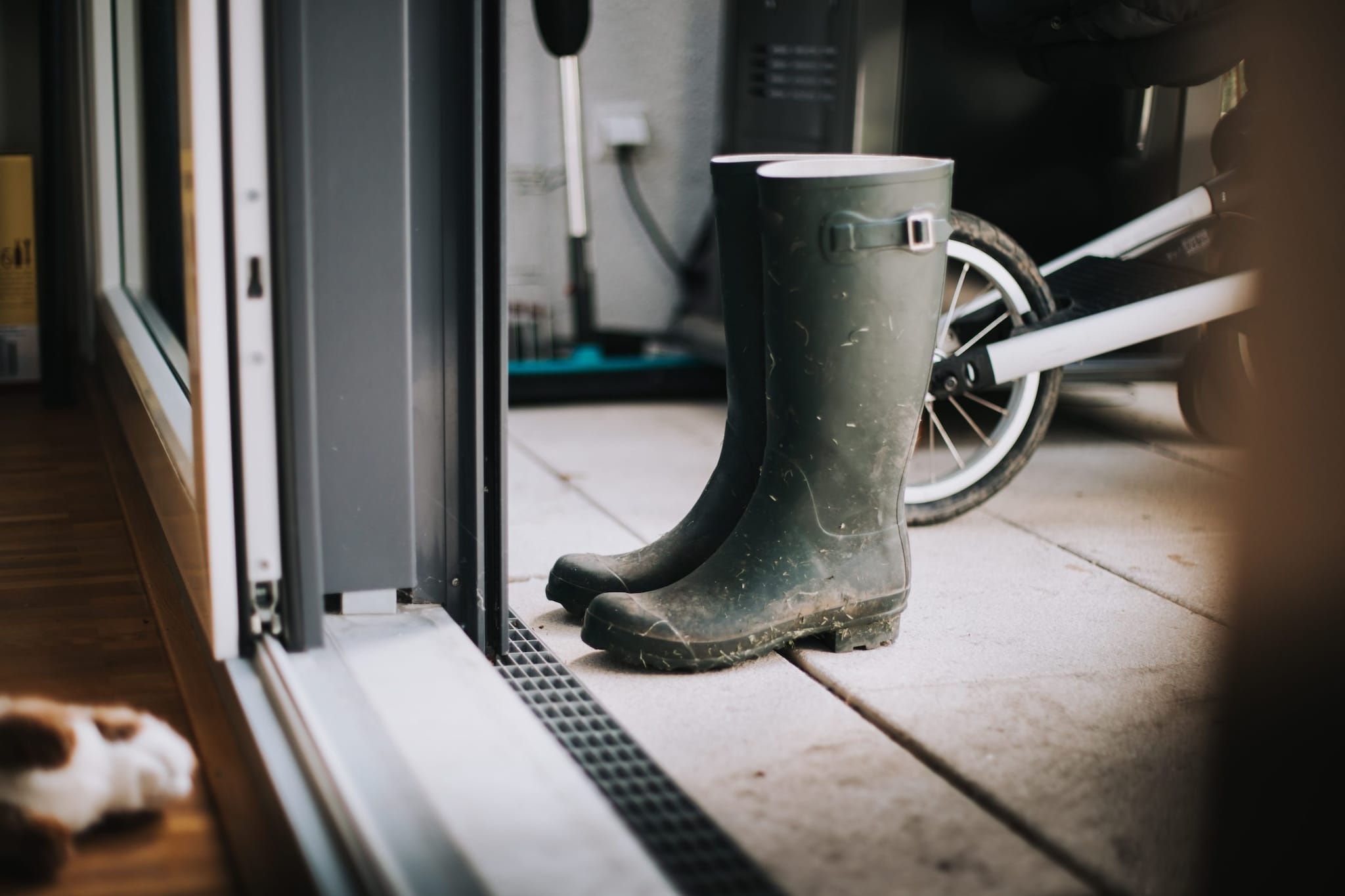 Image of boots on a porch outside in front of a sliding door.