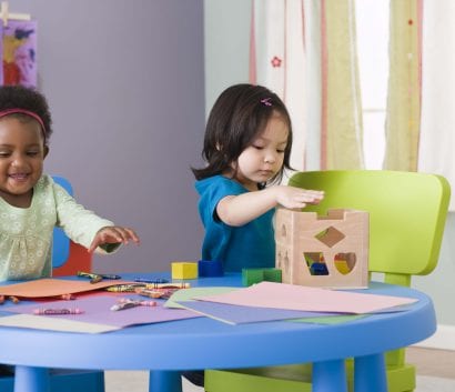 Two children playing with toys while sitting at a table.