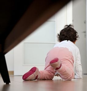 Baby girl crawling towards an open door.