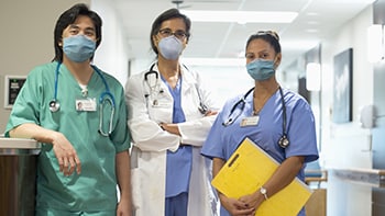 Three healthcare providers wearing scrubs and masks