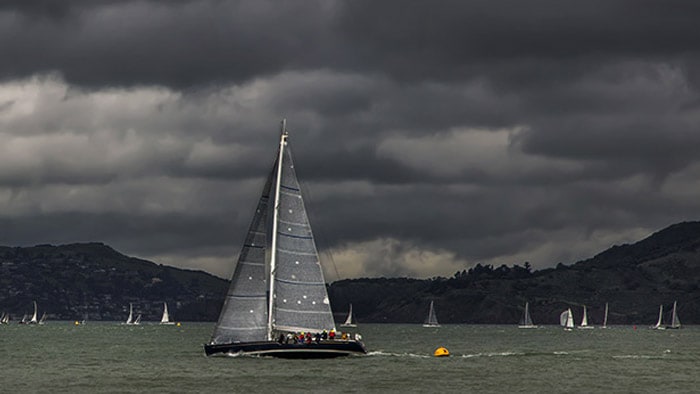 Boat sailing in the water with dark clouds looming overhead.
