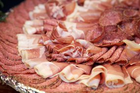 Close-up shot of a platter of cold cuts including salami, pepperoni and cured ham.