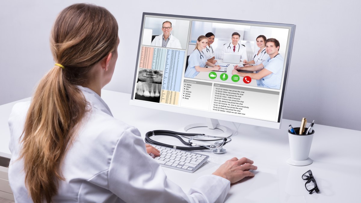 A doctor viewing a virtual meeting