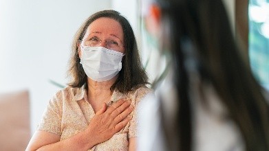 Paciente con una mascarilla hablando con su doctora.
