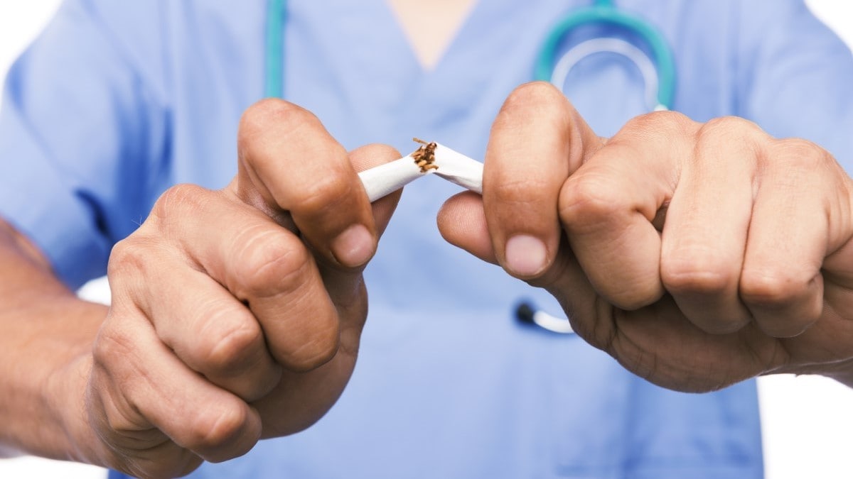 Foto de un doctor rompiendo un cigarrillo por la mitad