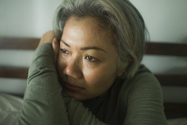Mature Asian lady looking sad and fatigued.