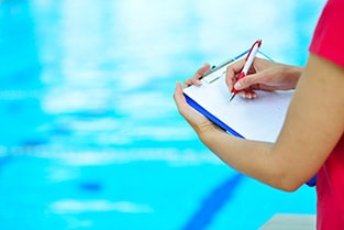Person filling out paperwork by a pool