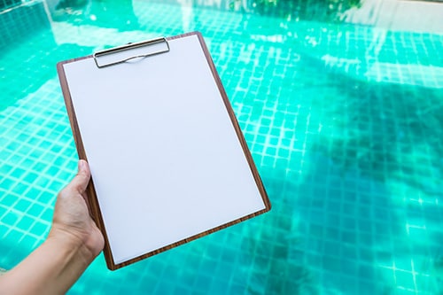 White paper on wooden clipboard over blurred blue water