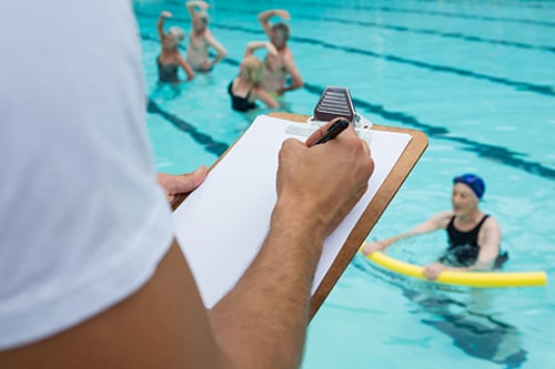 Person holding a clipboard with a sheet of paper on it looking at a pool