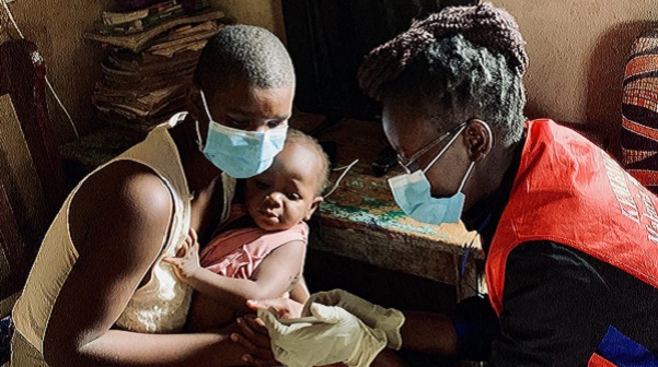 Mother holding sick child, talking to healthcare worker.