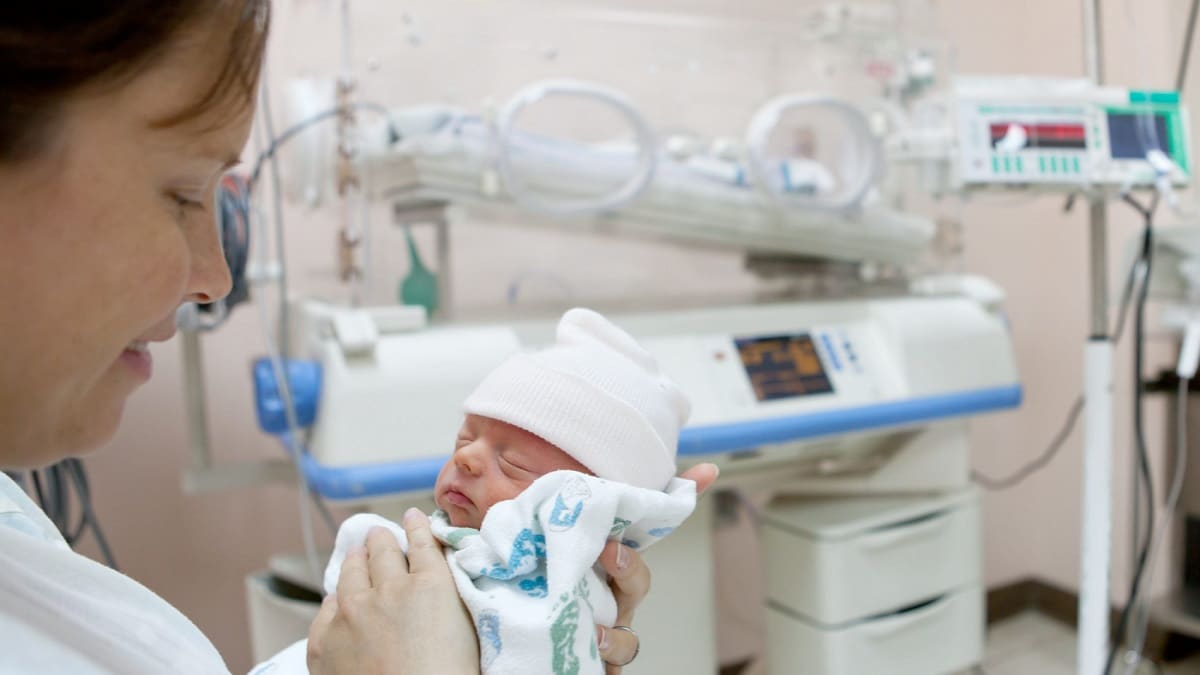 Woman holding preterm infant in a hospital setting