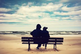 Father and daughter sitting on a bench on the beach