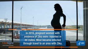 A pregnant woman looking out of an airport window